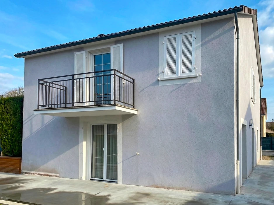 Pergola bioclimatique aluminium anthracite adossée à une maison, avec lames orientables au plafond et stores verticaux screen enroulables crème sur trois côtés
