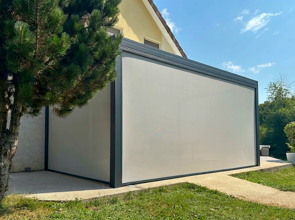 Pergola bioclimatique autoportante en aluminium anthracite, installée sur une terrasse en composite imitation bois