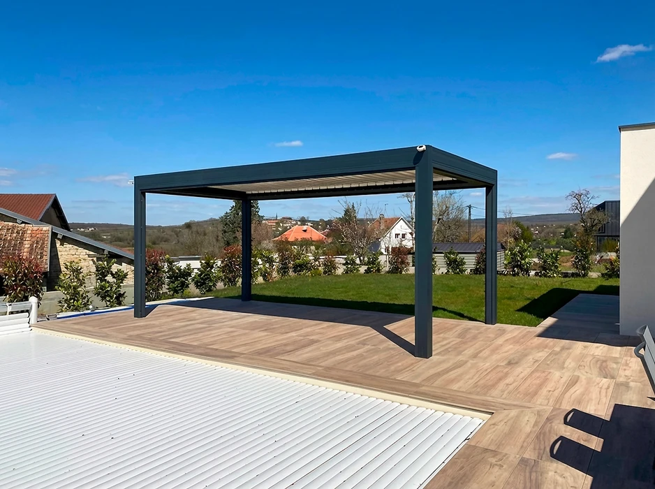 Pergola bioclimatique autoportante en aluminium anthracite, installée sur une terrasse en composite imitation bois