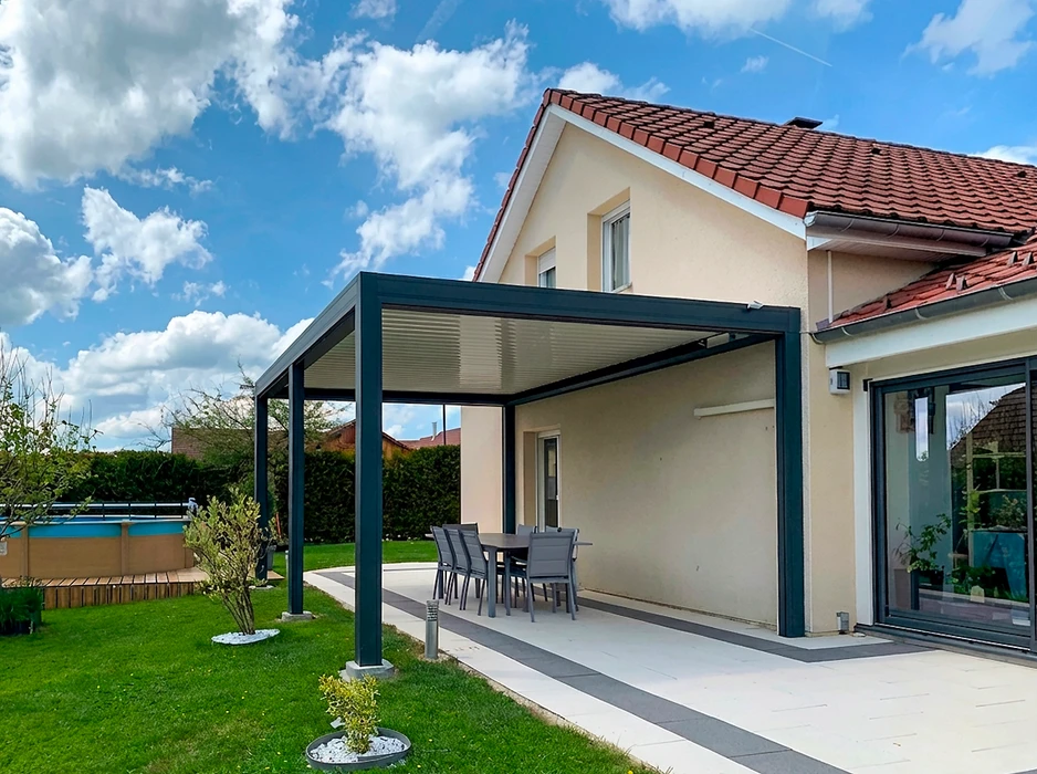 Pergola bioclimatique autoportante en aluminium anthracite, installée sur une terrasse en composite imitation bois