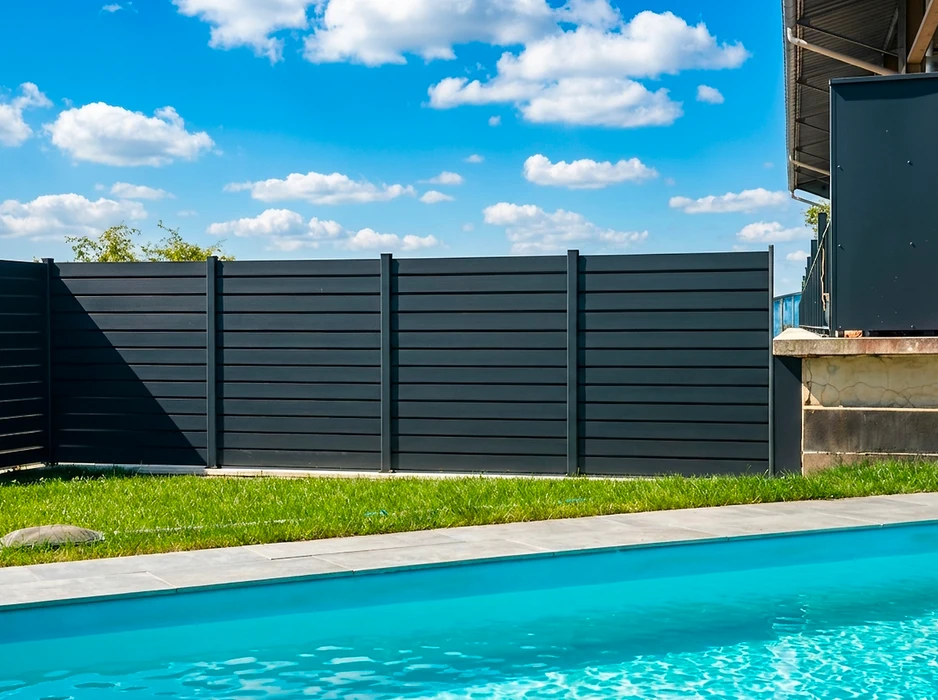 Pergola bioclimatique adossée à une maison, entièrement fermée par des stores verticaux coulissants en toile technique grise