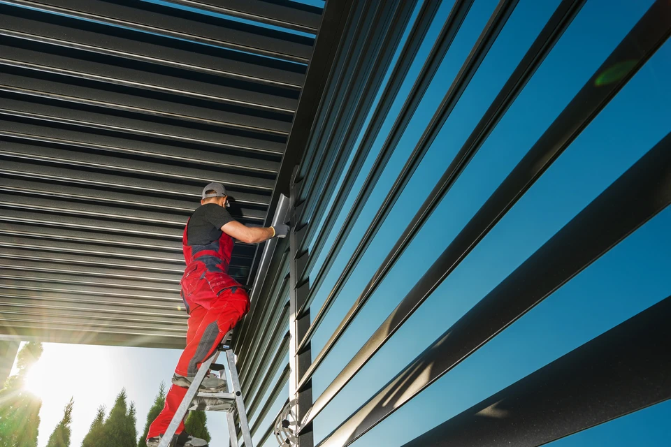 Homme en polo rose travaillant sur une terrasse en bois, installant ou réparant des lames de plancher extérieur